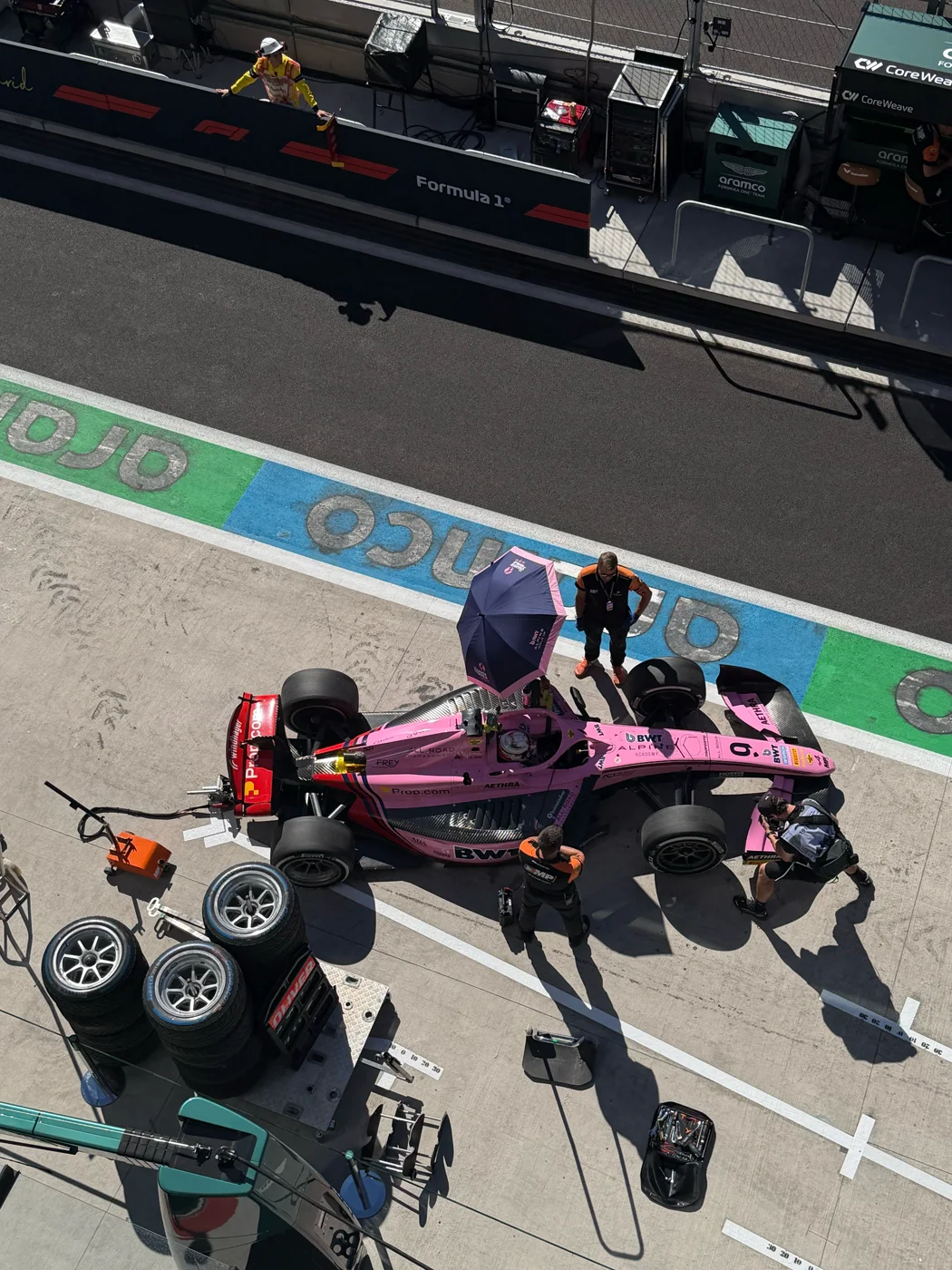 Monoplaza rosa y neumáticos en el pit lane, vistos desde arriba